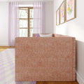 Bright pastel living room with blush pink upholstered sofa, sheer lavender curtains over wooden window, floral framed prints, decorative pillows and pastel area rug