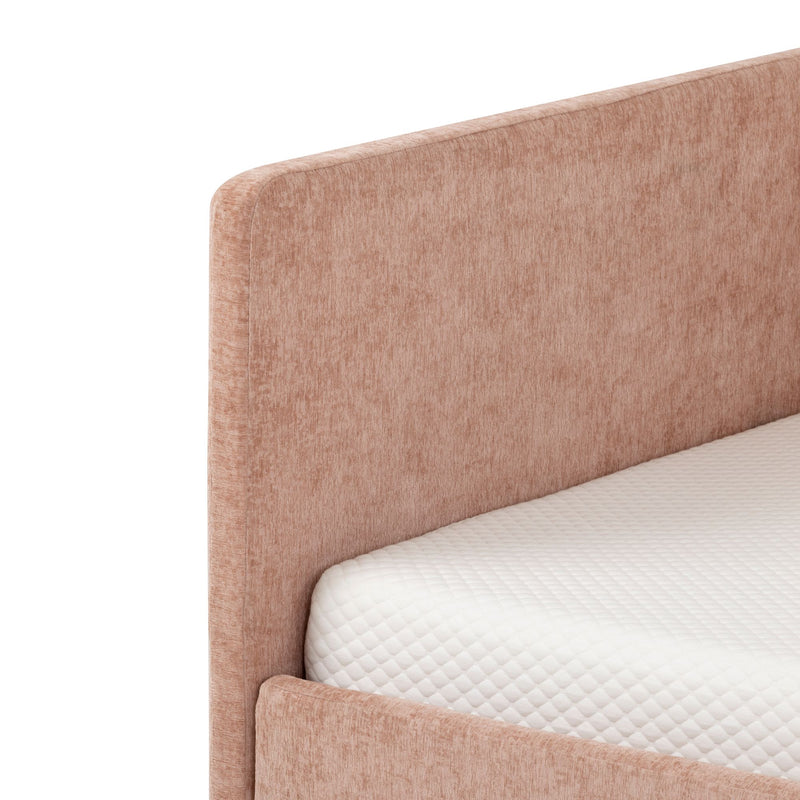 Close-up of blush pink upholstered fabric bed frame headboard and footboard with white quilted mattress
