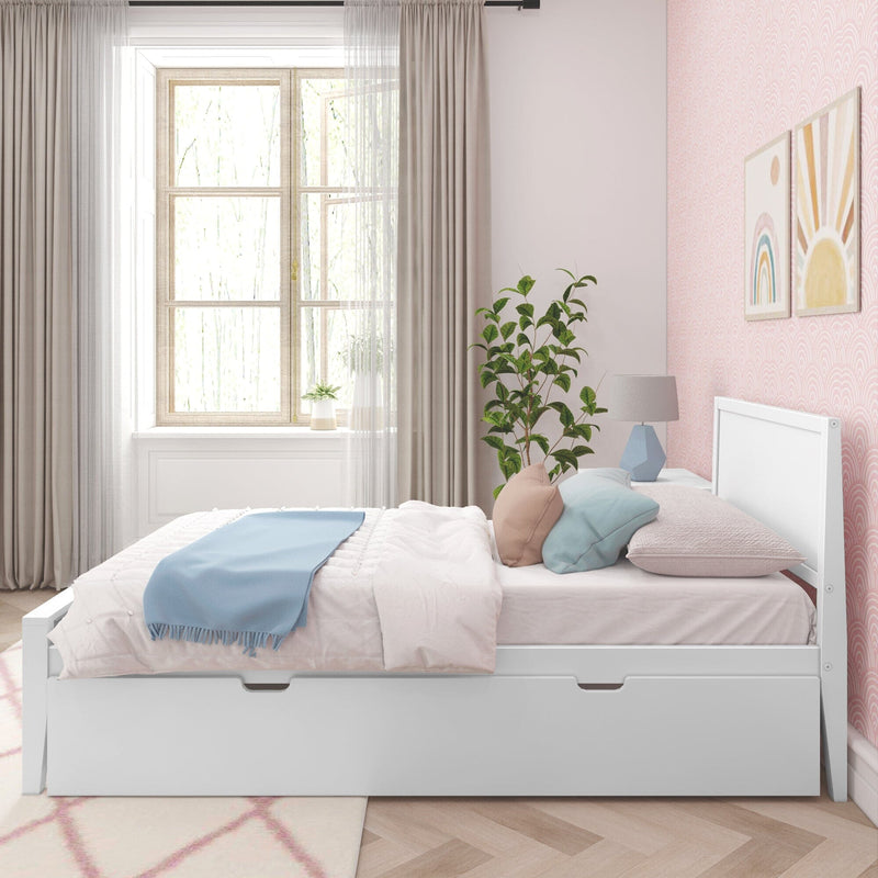 Sunlit pastel pink kids' bedroom with white storage twin bed, blue throw blanket, pastel pillows, geometric bedside lamp, potted plant and rainbow wall art