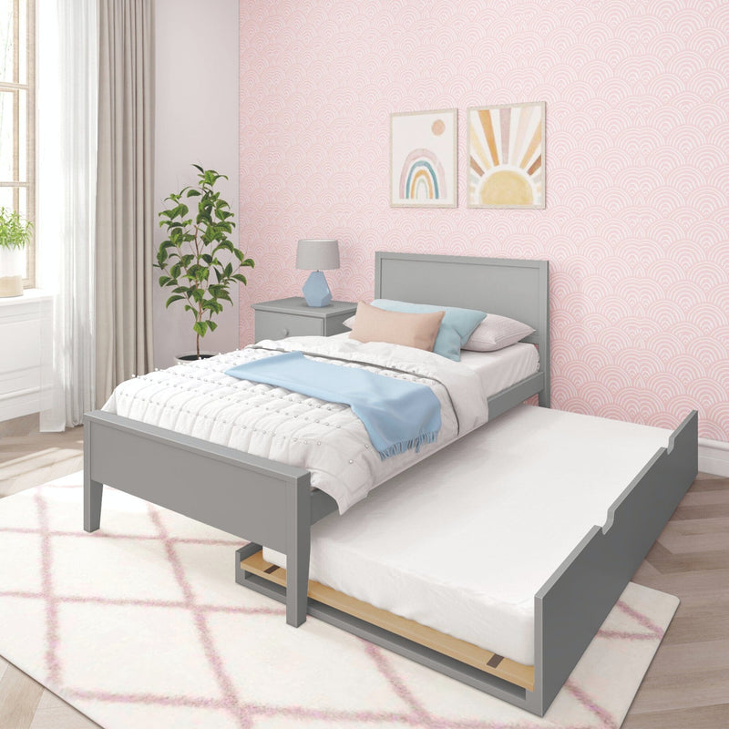 Gray twin bed with pull-out trundle in a modern pastel-themed bedroom, featuring pink patterned wallpaper and colorful decor.
