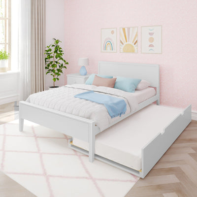 Pastel pink kids' bedroom with white trundle bed, blue and pink pillows, scalloped wallpaper, rainbow and sun wall art, bedside lamp and potted plant