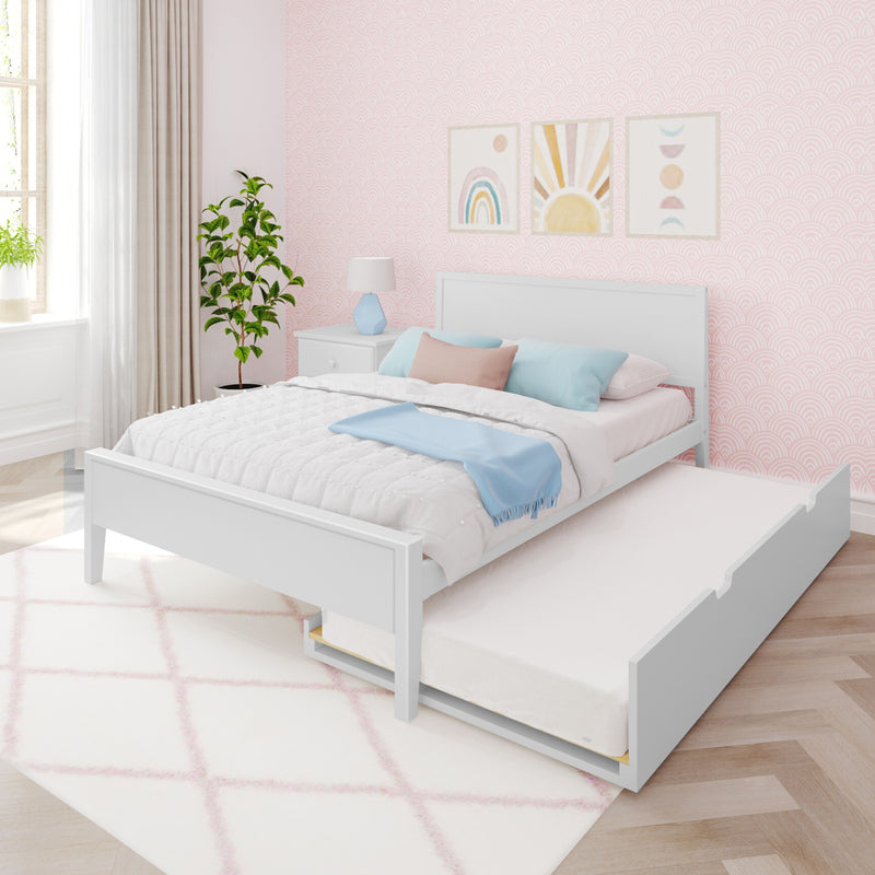 White wooden bed with pull-out trundle mattress in pastel pink bedroom with rainbow wall art, blue throw blanket, bedside lamp and indoor plant