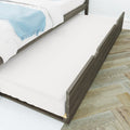 Wooden trundle bed with pull-out mattress, white bedding and light blue throw in modern kids' bedroom