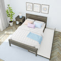 Modern bedroom with dark wooden bed frame and pull-out trundle, white quilted bedding and pastel pillows, wooden nightstand with blue lamp, potted plant, framed wall art and herringbone hardwood floor