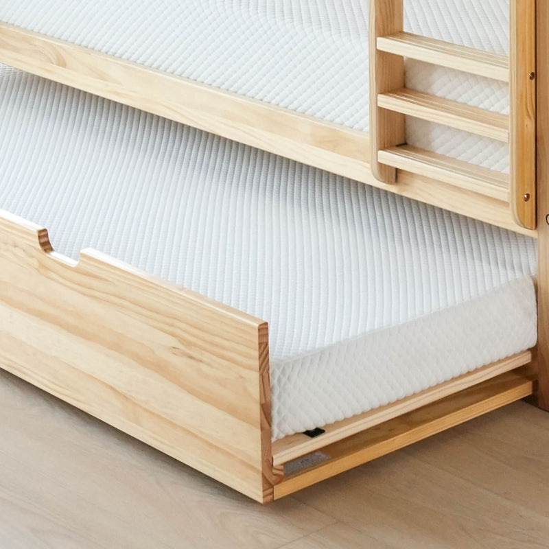 Wooden bunk bed with a comfortable mattress and pull-out trundle in a modern bedroom setting.