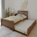 Space-saving wooden twin bed with pull-out trundle drawer, beige duvet and pillows, bedside table with lamp, potted plant and framed fruit wall art in a bright minimalist bedroom