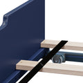 Close-up of blue platform bed frame with natural wood slats, black securing strap, metal center support beam and caster wheel