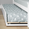 Grey giraffe-print trundle mattress tucked under a white wooden bed frame on light hardwood floor — kids' nursery bedding and fitted sheet