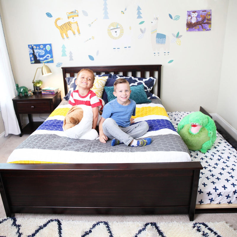 Children playing in a colorful bedroom with animal-themed wall decals and cozy bedding.