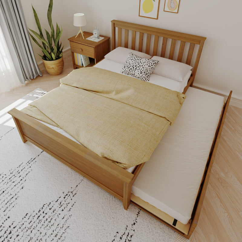 Wooden bed with pull-out trundle bed, yellow blanket, white pillows, modern bedroom furniture with nightstand and indoor plant.