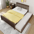 Wooden trundle bed with pull-out mattress, yellow duvet and polka-dot pillow next to dark wood nightstand, potted plant, lamp and light wood floor in modern bedroom