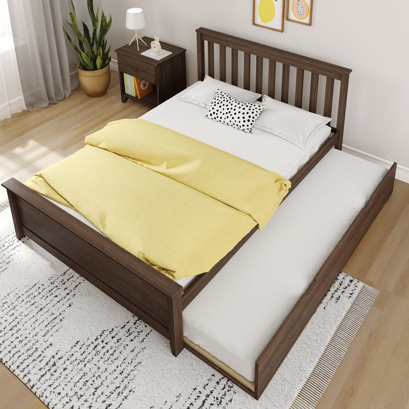 Wooden trundle bed with pull-out mattress, yellow duvet and polka-dot pillow next to dark wood nightstand, potted plant, lamp and light wood floor in modern bedroom