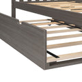 Modern gray wood platform bed frame with wooden slats and black central metal support beam, close-up of slatted mattress base