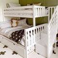 White wooden L-shaped bunk bed with built-in stairs, gray plaid bedding, black cross quilt, fox plush toy, green accent wall and under-bed storage in a modern kids' bedroom