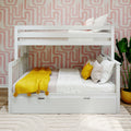 White wooden bunk bed in modern children's bedroom with pink geometric wallpaper, yellow throw blanket, decorative pillows, and potted plant