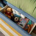 Playroom toy storage drawer with teddy bear, plush animals, toy dinosaur and "Diary of a Wimpy Kid" children's book beside blue sofa and green cushion