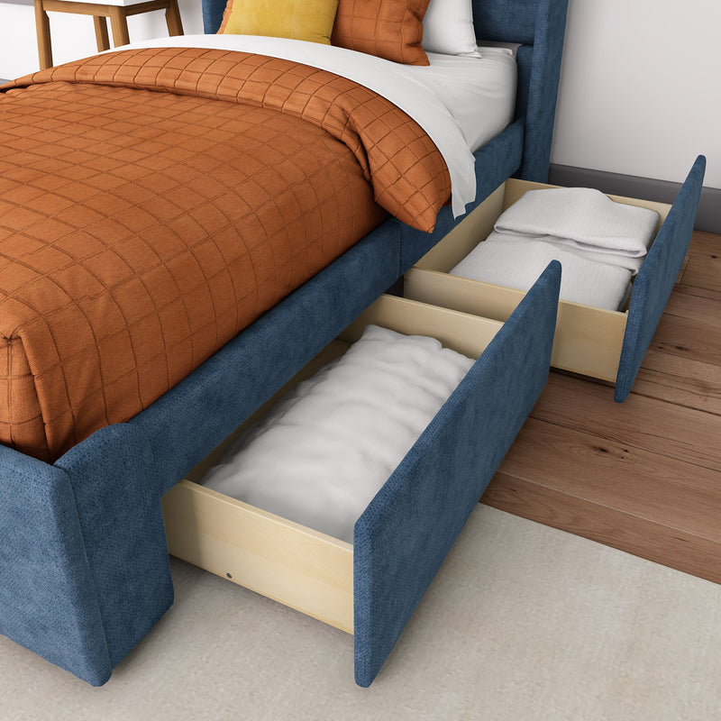 Blue upholstered storage bed with open drawers revealing linens, hardwood floor background.