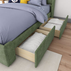 Green upholstered bed with under-bed storage drawers, containing folded blankets, on wooden floor.