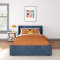 Children's bedroom with orange bedding, blue bed frame, framed wall art, and bedside table with lamp and alarm clock.