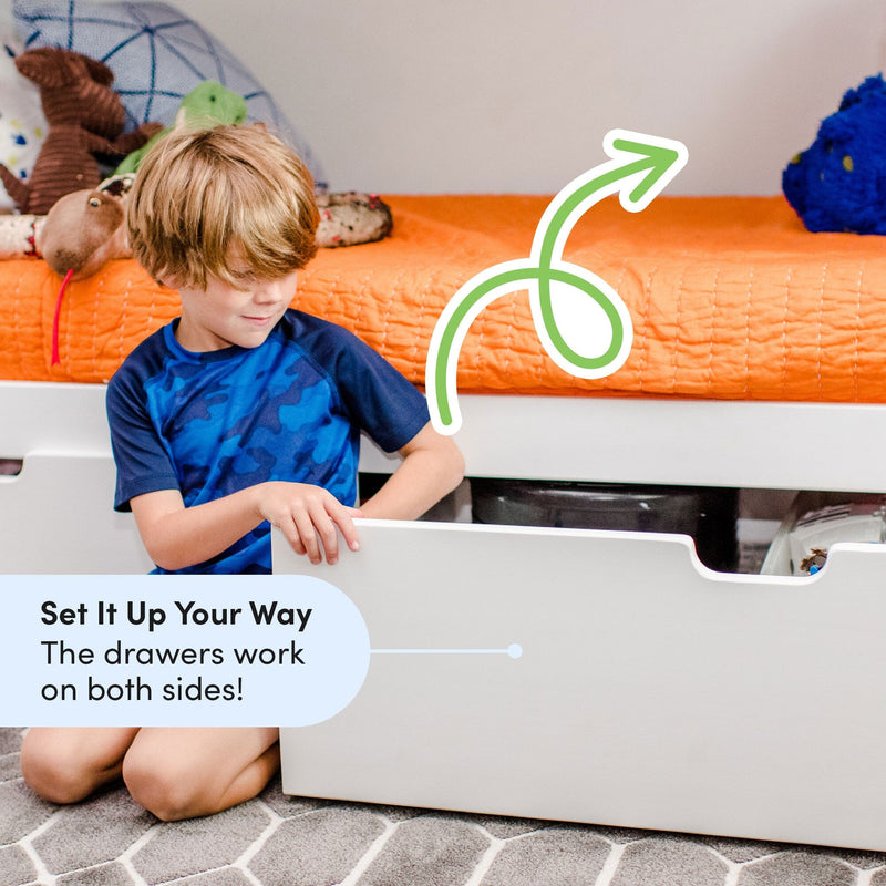 Kids bed with under-bed storage — young boy opening white storage drawer under platform bed with orange quilt, reversible drawer design and bedroom organization solution