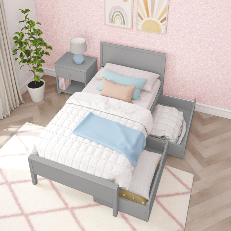 Gray twin bed with storage drawers in a children's bedroom, pink wallpaper, bright decor, and wooden floor.