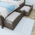 Gray wood trundle bed with under-bed pull-out storage drawers, white quilted bedding and light blue throw blanket
