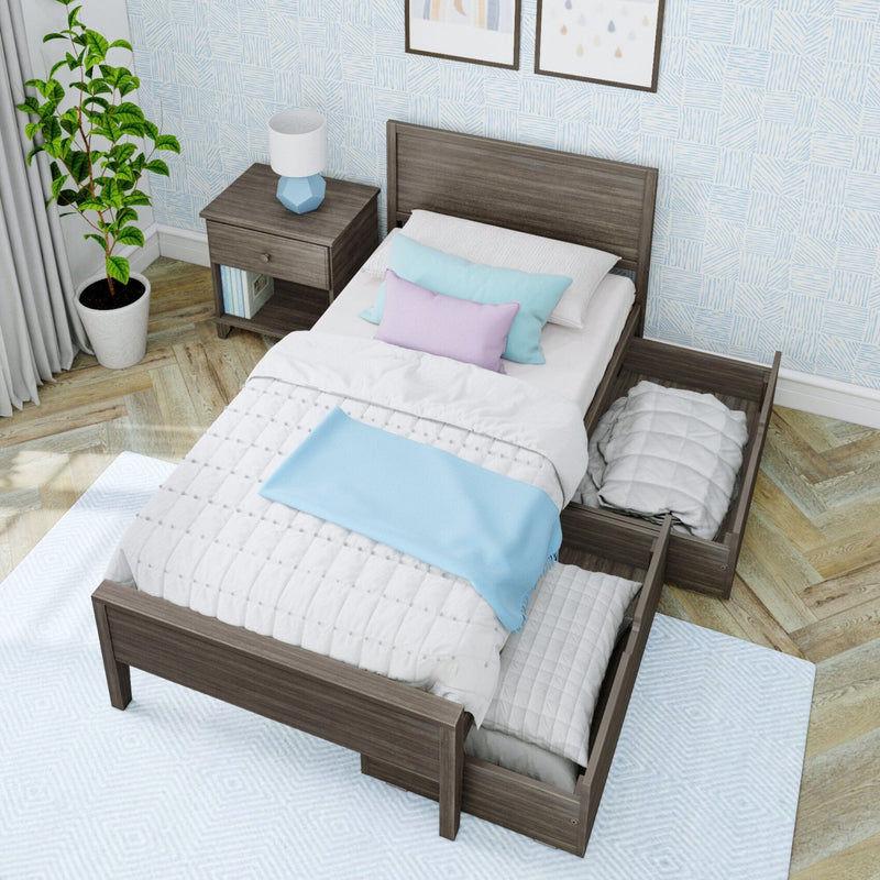 Wooden twin storage bed with pull-out drawers, white quilt and blue throw in a modern small bedroom with nightstand, lamp and potted plant