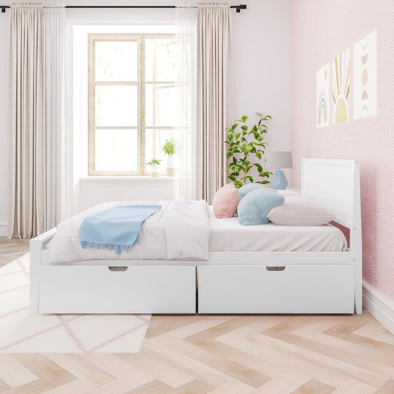 Bright Scandinavian-style kids' bedroom with a white storage bed and two under-bed drawers, pastel pink accent wall with rainbow prints, soft white and blue bedding and throw pillows, potted plant beside a sunlit window and herringbone hardwood floor.