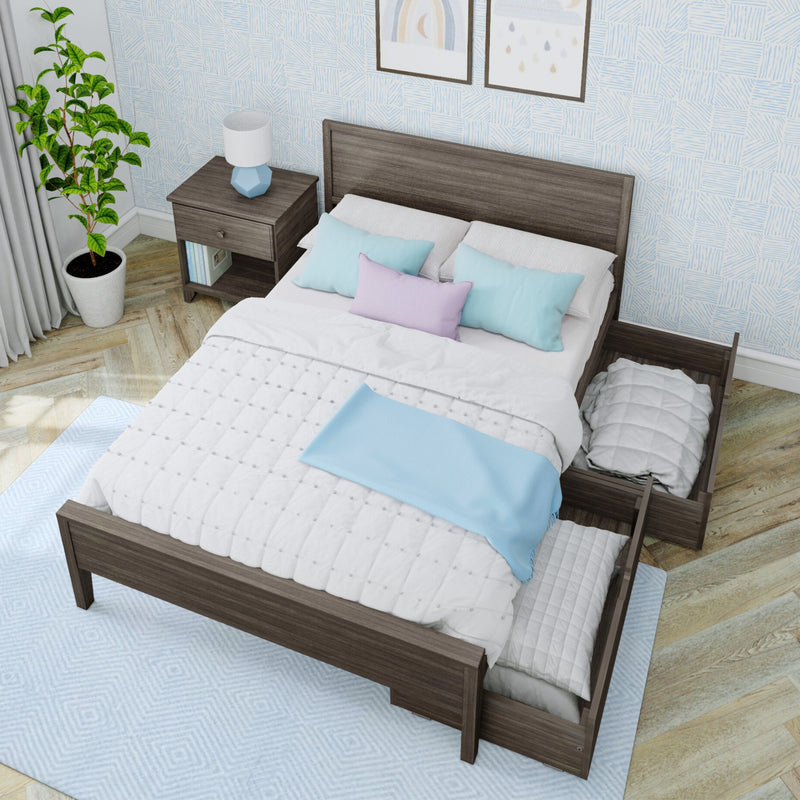 Modern bedroom: dark wood platform bed with trundle, white quilt and pastel pillows, nightstand with blue lamp, potted plant.
