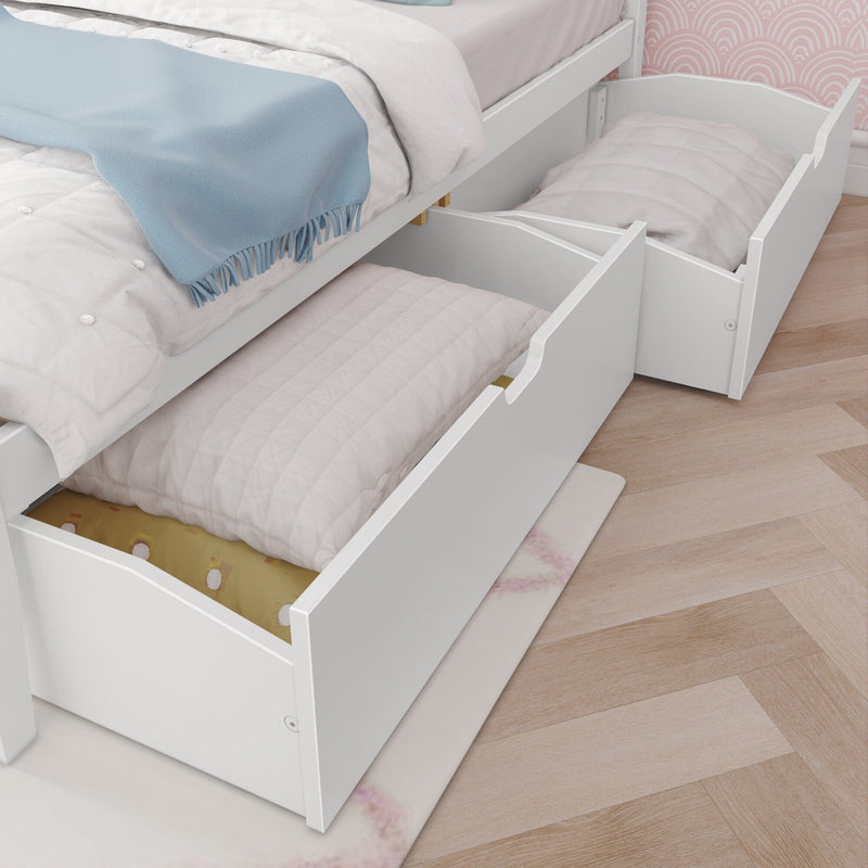 White wooden bed with two pull-out under-bed storage drawers (trundle) filled with folded blankets and pillows on a herringbone wood floor in a child's bedroom