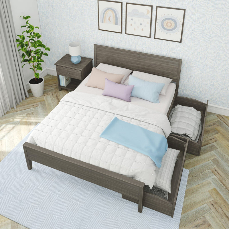 Modern grey wood platform storage bed with pull-out drawers, white quilt and pastel pillows in a bright minimalist bedroom with nightstand, lamp, potted plant, framed wall art and herringbone wood floor.