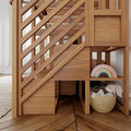 Wooden under-stair storage and oak staircase with diagonal balusters, built-in cubbies holding a wicker basket, plush bunny and pastel wooden rainbow toy in a cozy kids play nook