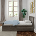 Minimalist bedroom interior with wooden storage bed, light-blue polka-dot duvet, potted plants on windowsill, fiddle-leaf fig, neutral curtains and framed animal art