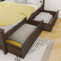 Dark wood platform bed with pull-out underbed storage drawers storing folded bedding, yellow duvet and patterned pillows in a modern bedroom