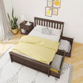 Scandinavian bedroom with dark wood platform bed and under-bed trundle storage, yellow duvet, polka-dot pillow, bedside table, lamp and potted plant