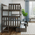 Gray wooden twin-over-twin bunk bed with built-in under-bed storage drawers in a modern kids' bedroom with blue patterned wallpaper, light blue curtains, potted plant, bench by a large window and hardwood floors