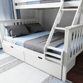 White wooden bunk bed with ladder and under-bed storage drawers, full-size lower bed and twin upper with blue and gray bedding in a modern kids' bedroom on hardwood floor and patterned area rug