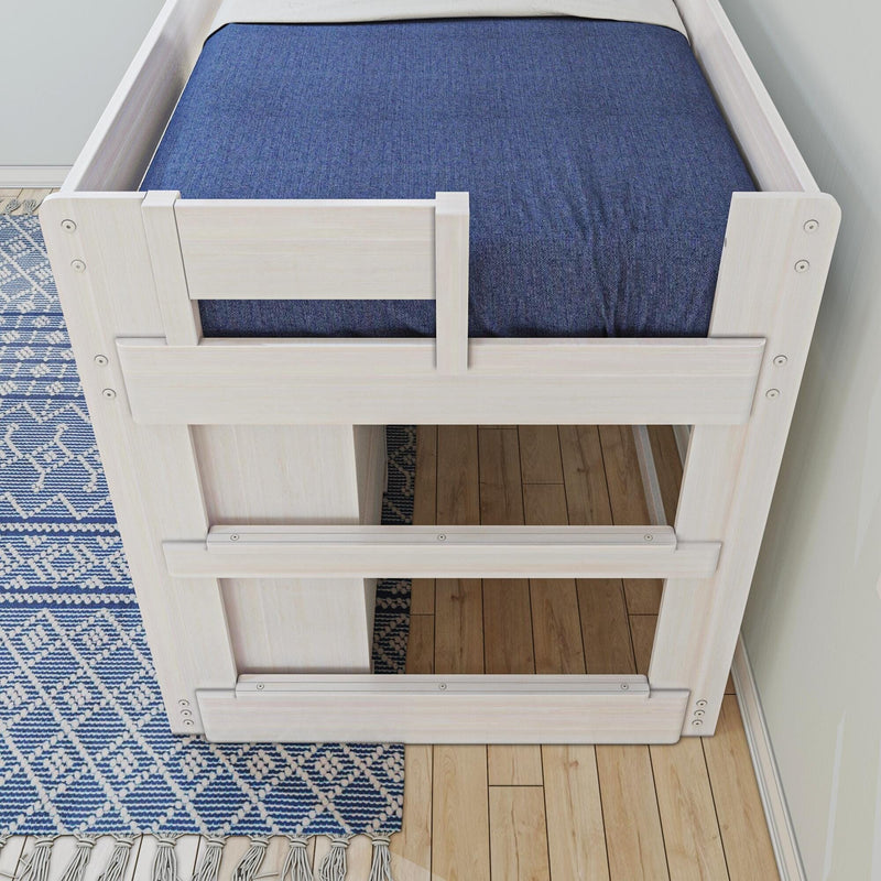White wooden loft bed with blue bedding on a patterned rug and wooden floor.