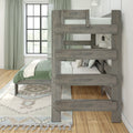 Gray reclaimed-wood bunk bed in a coastal farmhouse bedroom with green bedding, patterned rug, black-framed window and wall sconce