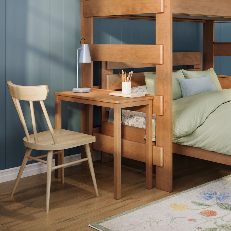 Oak kids' bunk bed with built-in desk and chair, study lamp and pencil cup, green bedding and floral rug on hardwood floor