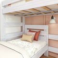 Whitewashed wooden twin bunk bed with exposed slats, floral bedding, textured pillows and wall sconce in cozy kids' bedroom