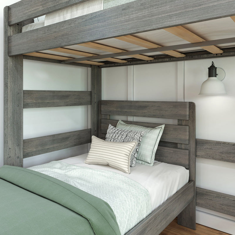 Gray rustic twin-over-twin wooden bunk bed with green duvet, textured white throw, patterned pillows and wall sconce in a modern farmhouse bedroom