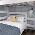 Whitewashed wooden bunk bed lower with gray quilt, white speckled sheets, navy-dot pillows and yellow geometric accent pillow under a wall-mounted reading lamp on a gray paneled wall in a modern bedroom