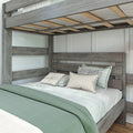 Rustic gray wood bunk bed with lower bed dressed in sage green duvet, white textured sheets and decorative patterned pillows in a modern farmhouse bedroom