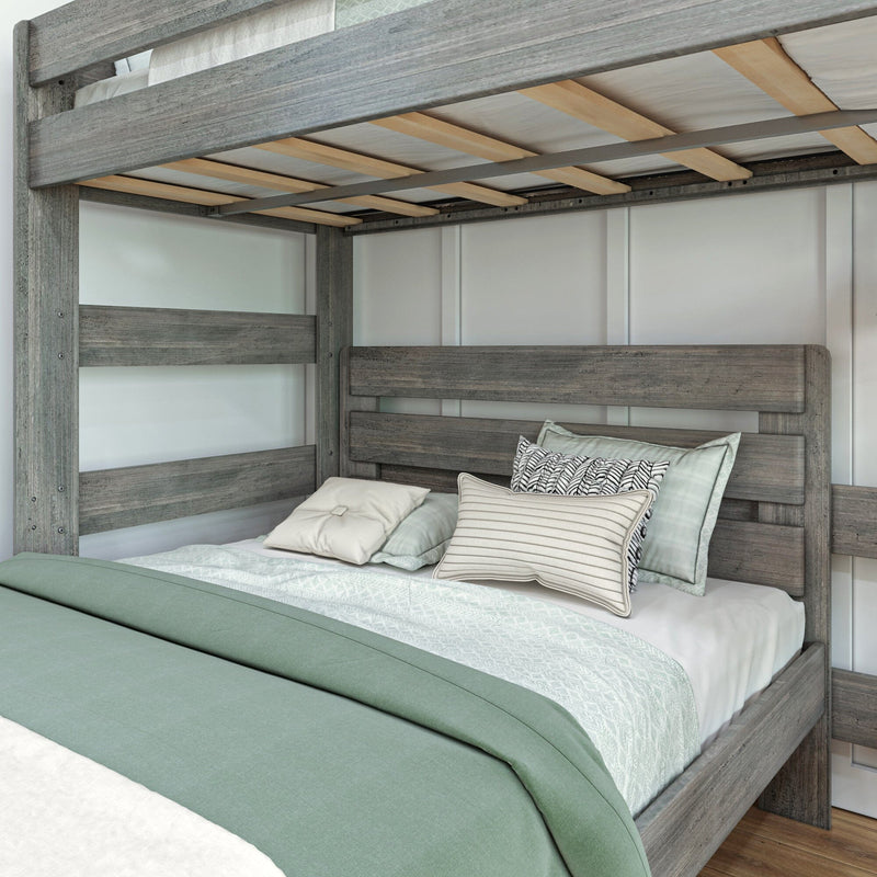 Rustic gray wood bunk bed with lower bed dressed in sage green duvet, white textured sheets and decorative patterned pillows in a modern farmhouse bedroom