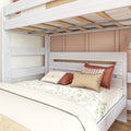 Whitewashed wooden bunk bed with full-size lower bed, neutral floral duvet and layered decorative throw pillows in a cozy modern bedroom