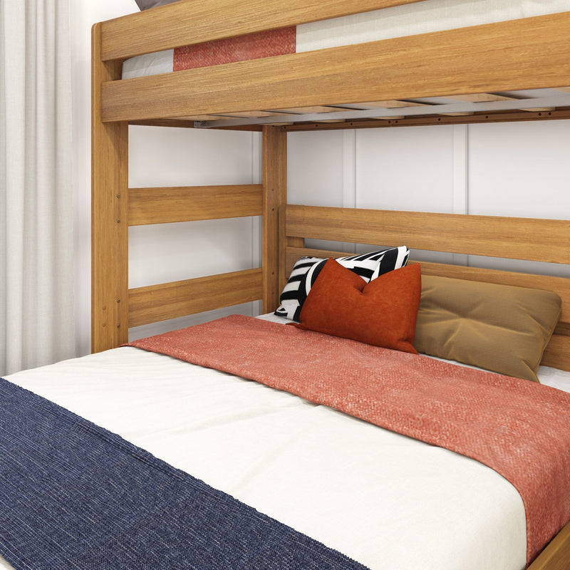 Close-up of a natural wood bunk bed frame with coral bedding, rust-orange throw pillows and a black-and-white striped accent pillow over a navy throw blanket, staged against white curtains in a modern kids' bedroom