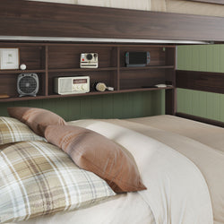 Cozy bedroom headboard with built-in dark wood shelves and green paneled wall, plaid pillows and beige bedding, vintage radio, Polaroid camera, headphones and handheld game console
