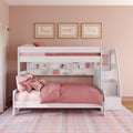 White twin-over-full wooden bunk bed with storage stairs, built-in shelves and pink bedding in a girl's bedroom with plaid rug and framed horse prints