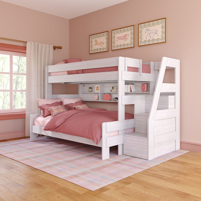 White wooden twin-over-full bunk bed with storage staircase and built-in shelves, pink and blush bedding in a pastel girls' bedroom with hardwood floors